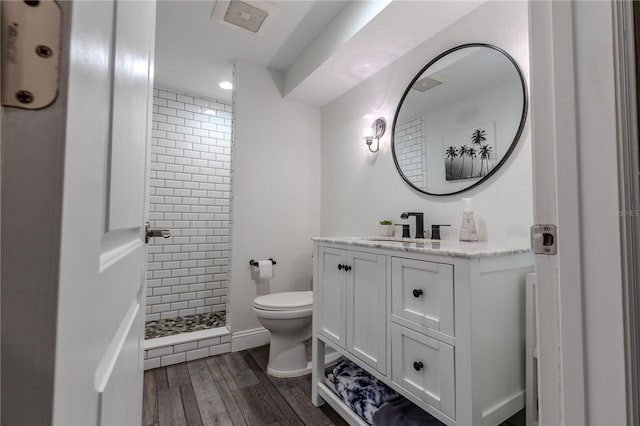 bathroom with vanity, visible vents, toilet, wood finished floors, and a stall shower