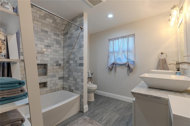 bathroom featuring baseboards, a sink, toilet, double vanity, and wood finished floors