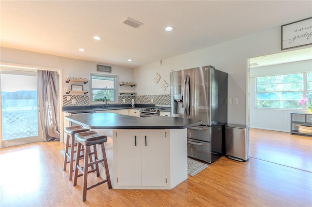 kitchen with open shelves, dark countertops, light wood-style floors, visible vents, and appliances with stainless steel finishes