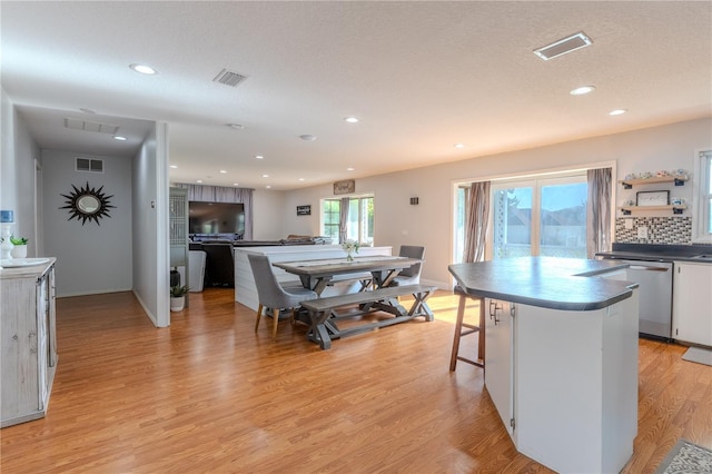 kitchen featuring visible vents, light wood-type flooring, dark countertops, and stainless steel dishwasher