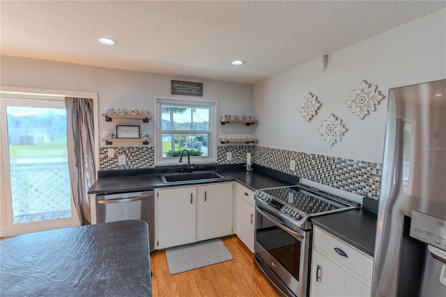 kitchen with open shelves, a sink, appliances with stainless steel finishes, dark countertops, and a textured ceiling