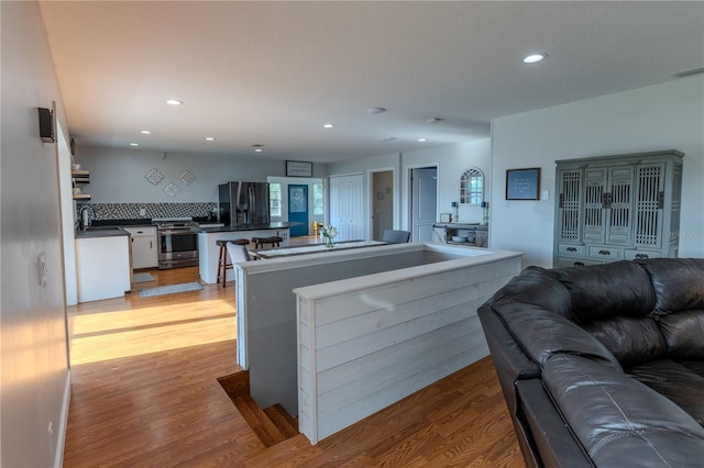 living room with light wood-style flooring, visible vents, and recessed lighting