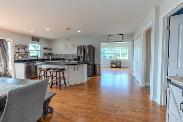 kitchen featuring dark countertops, white cabinets, light wood finished floors, and stainless steel appliances