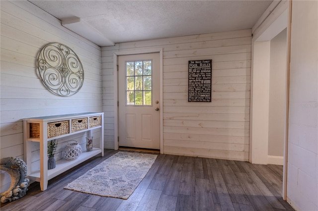 doorway featuring wood walls, a textured ceiling, and dark wood finished floors