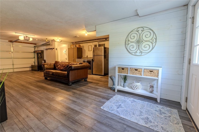 living area featuring a textured ceiling, wood finished floors, and wooden walls