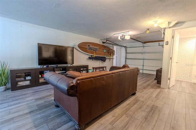 living room featuring light wood finished floors, a garage, and a textured ceiling