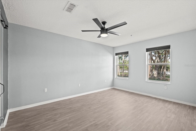 unfurnished room featuring wood finished floors, ceiling fan, a textured ceiling, and baseboards