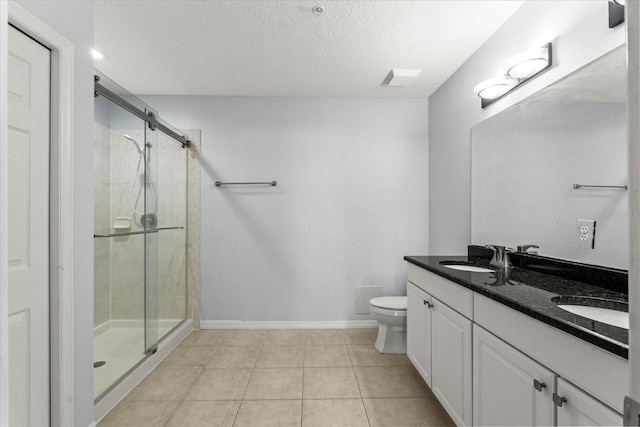 bathroom featuring a stall shower, toilet, a textured ceiling, baseboards, and tile patterned floors