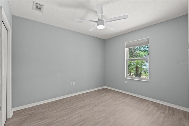 unfurnished room featuring wood finished floors, ceiling fan, baseboards, and a textured ceiling
