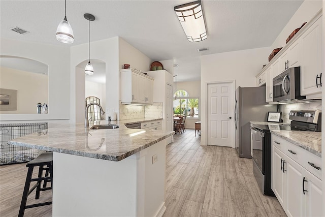 65 Esperanto Dr, Palm Coast, FL 32164 - kitchen featuring a kitchen breakfast bar, a sink, stainless steel appliances, light wood-style flooring, and visible vents