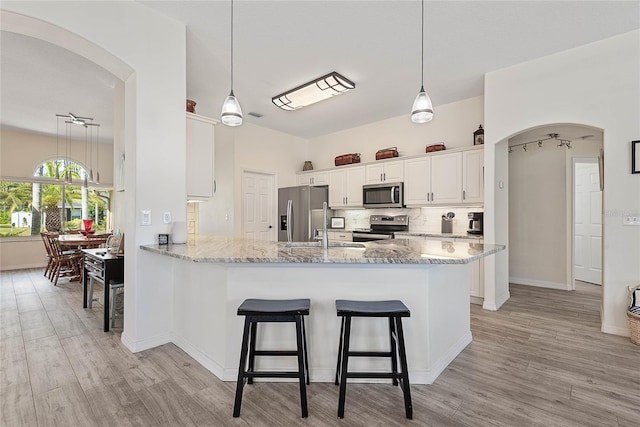 65 Esperanto Dr, Palm Coast, FL 32164 - kitchen with arched walkways, appliances with stainless steel finishes, white cabinetry, and light wood-style flooring