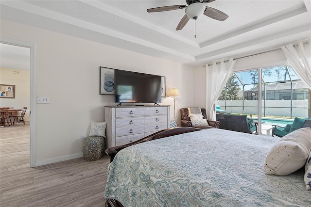 65 Esperanto Dr, Palm Coast, FL 32164 - bedroom featuring a tray ceiling, wood finished floors, a ceiling fan, baseboards, and access to outside