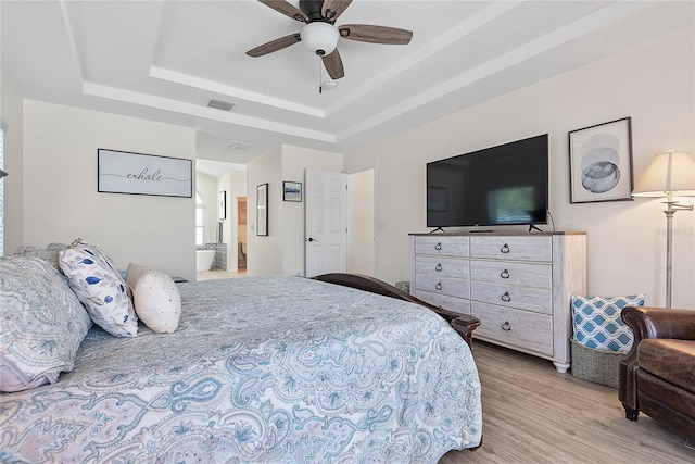 65 Esperanto Dr, Palm Coast, FL 32164 - bedroom featuring connected bathroom, light wood-style floors, visible vents, and a raised ceiling