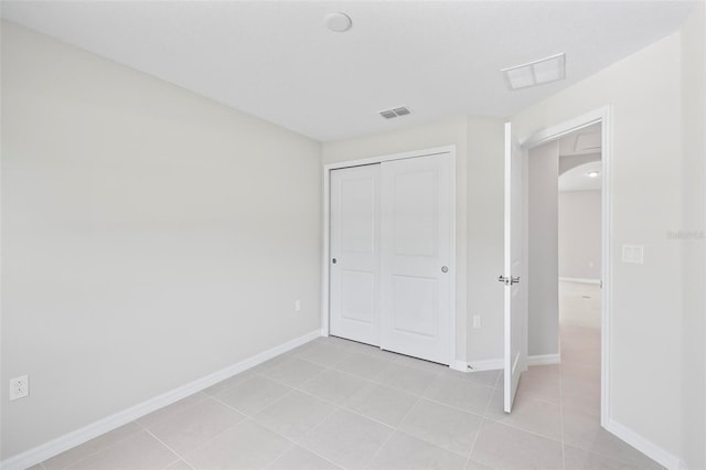 55 Ryan Dr, Palm Coast, FL 32164 - unfurnished bedroom featuring arched walkways, light tile patterned floors, a closet, and baseboards
