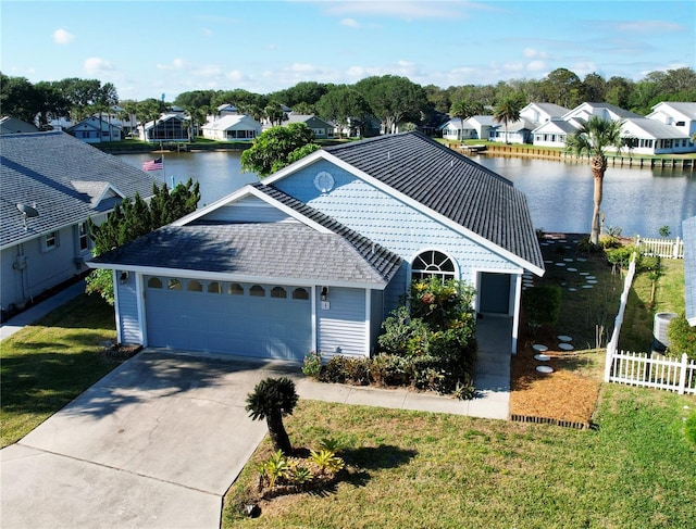 ranch-style house featuring fence, an attached garage, a residential view, and a water view