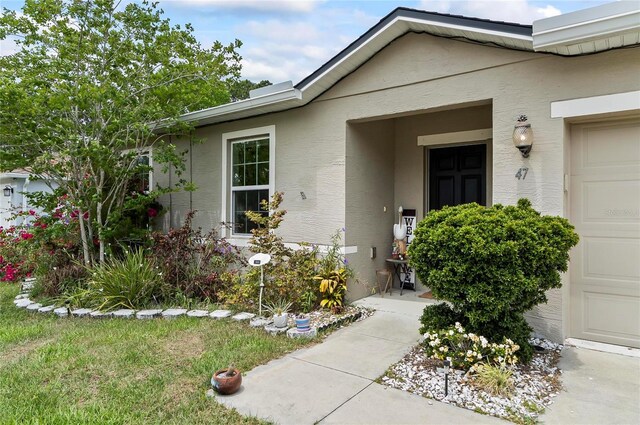 47 Raleigh Dr, Palm Coast, FL 32164 - doorway to property with an attached garage and stucco siding