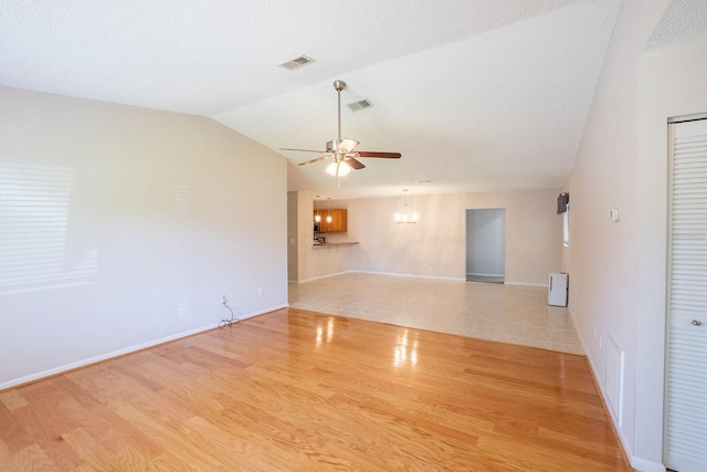 empty room featuring ceiling fan, visible vents, wood finished floors, baseboards, and lofted ceiling