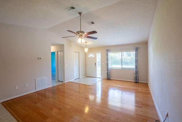 spare room with a textured ceiling, ceiling fan, visible vents, and light wood-type flooring