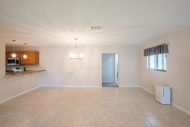 unfurnished living room featuring visible vents, baseboards, and a chandelier