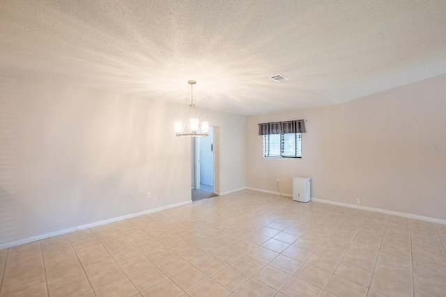 unfurnished room featuring a textured ceiling, visible vents, light tile patterned floors, baseboards, and a notable chandelier