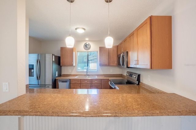 kitchen with light countertops, hanging light fixtures, appliances with stainless steel finishes, and a sink