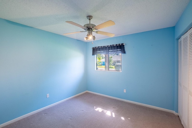 unfurnished room with carpet floors, a ceiling fan, baseboards, and a textured ceiling