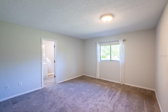 empty room featuring carpet floors, baseboards, and a textured ceiling