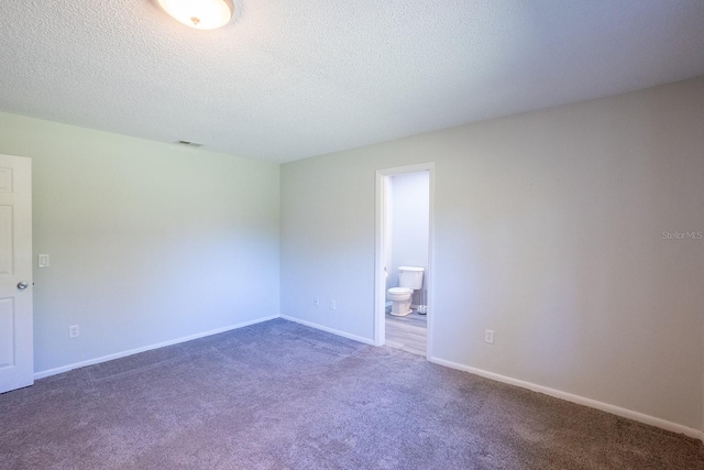 carpeted spare room featuring a textured ceiling, baseboards, and visible vents