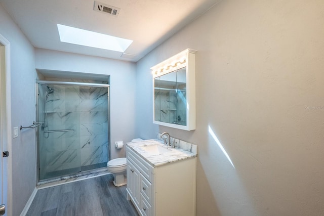 full bath with visible vents, wood finished floors, toilet, a marble finish shower, and a skylight