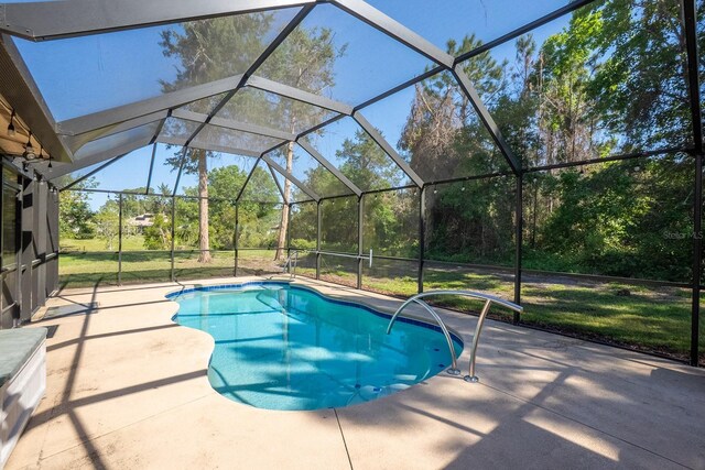 pool featuring a lawn, glass enclosure, and a patio area