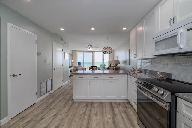 1155 Ocean Shore Blvd Unit 702, Ormond Beach, FL 32176 - kitchen featuring backsplash, white microwave, a peninsula, electric range, and ceiling fan
