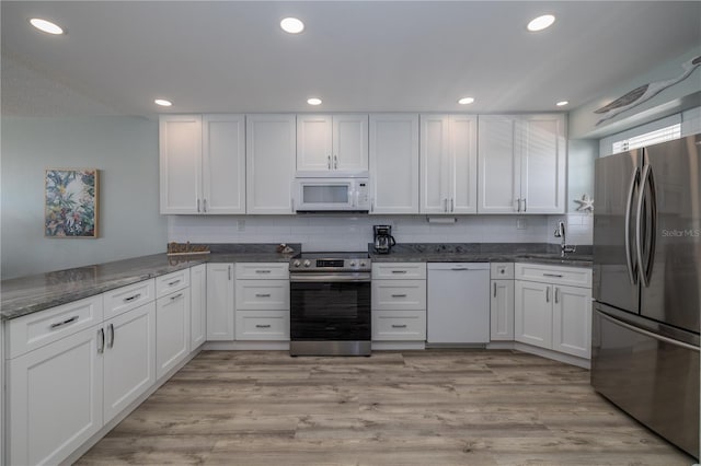 1155 Ocean Shore Blvd Unit 702, Ormond Beach, FL 32176 - kitchen featuring a sink, dark stone countertops, tasteful backsplash, white cabinetry, and appliances with stainless steel finishes