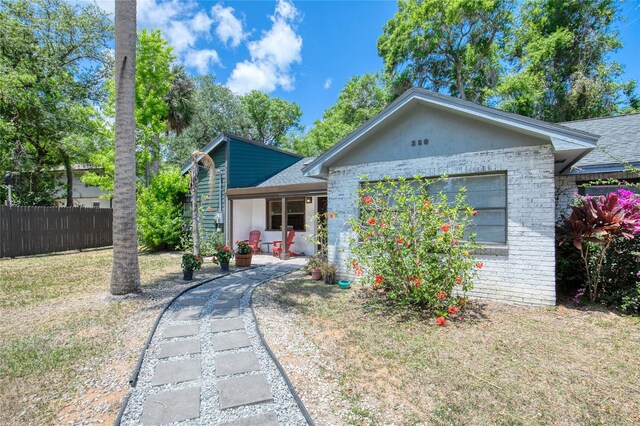 330 Wall Ave, Ormond Beach, FL 32174 - ranch-style house featuring brick siding, a shingled roof, a front lawn, and fence