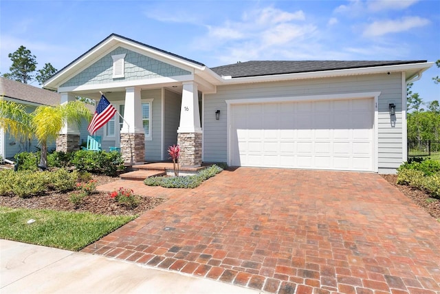 view of front facade featuring an attached garage, a porch, stone siding, and decorative driveway