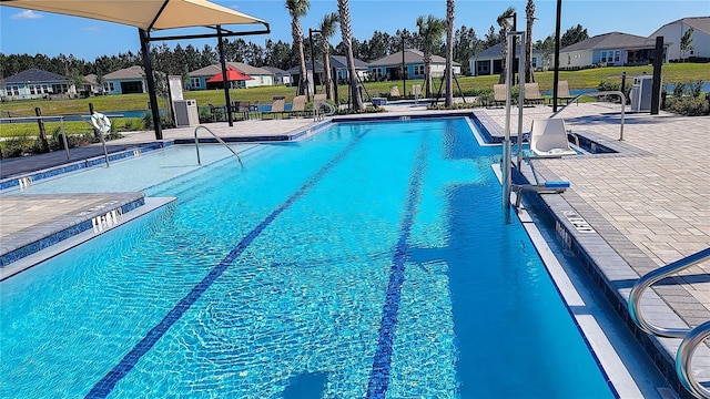 community pool featuring a patio area, a lawn, and a residential view