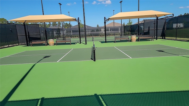 view of tennis court with community basketball court and fence
