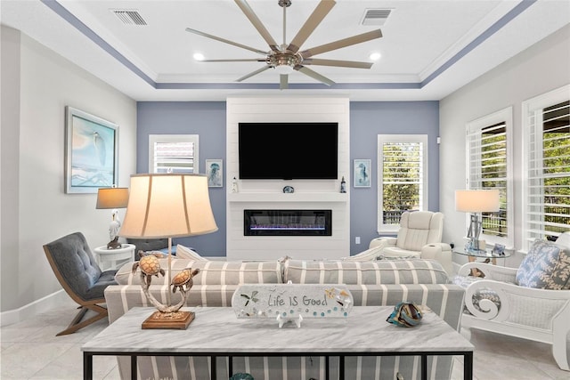 living area featuring a ceiling fan, visible vents, and a raised ceiling