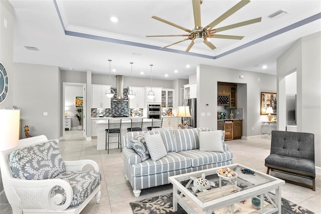 living area with a tray ceiling, visible vents, and recessed lighting