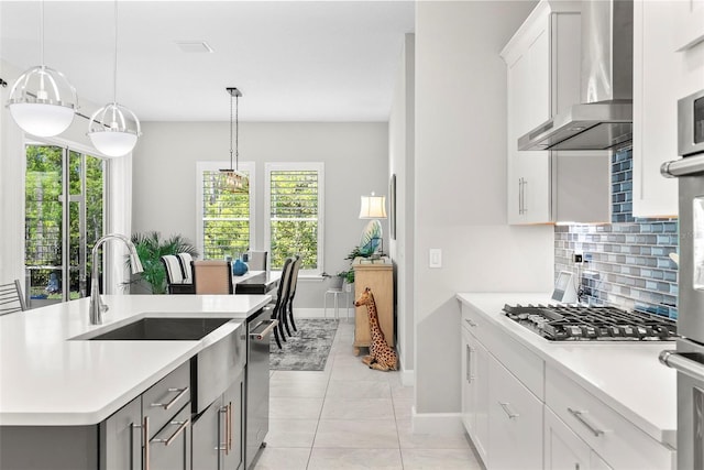 kitchen featuring light countertops, tasteful backsplash, wall chimney exhaust hood, and appliances with stainless steel finishes