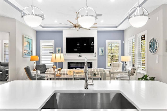 kitchen featuring open floor plan, light countertops, a tray ceiling, and a fireplace