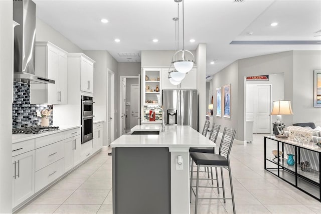 kitchen featuring light tile patterned floors, wall chimney exhaust hood, stainless steel appliances, and a sink