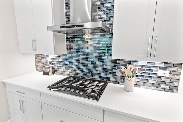 kitchen with stainless steel gas cooktop, island range hood, white cabinetry, and light countertops
