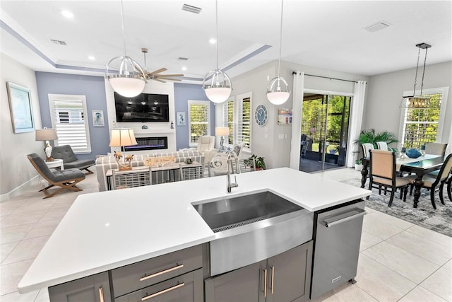 kitchen with a sink, open floor plan, light tile patterned floors, gray cabinets, and light countertops