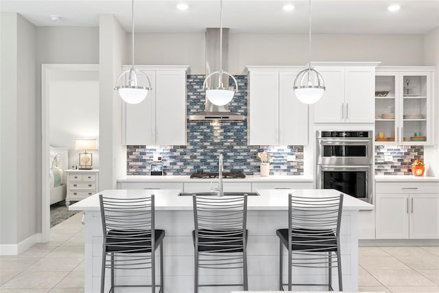 kitchen featuring decorative backsplash, a breakfast bar, stainless steel appliances, a center island with sink, and light countertops