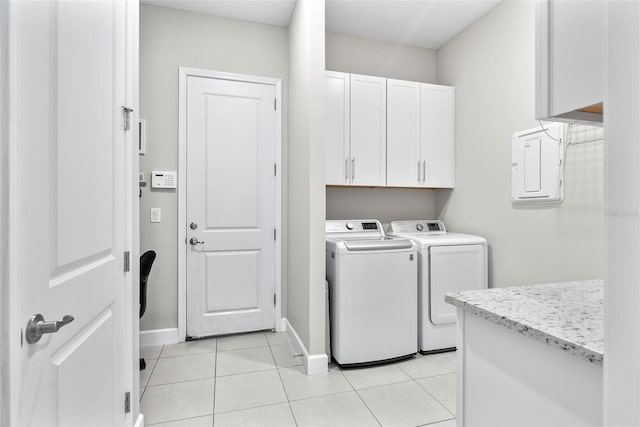 washroom featuring light tile patterned flooring, electric panel, baseboards, washer and dryer, and cabinet space