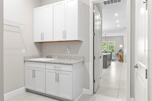interior space featuring a sink, light tile patterned floors, baseboards, visible vents, and recessed lighting