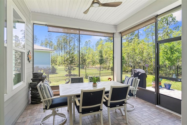 sunroom with a ceiling fan, outdoor dining space, and a healthy amount of sunlight