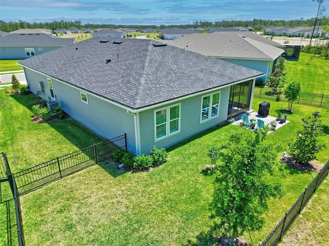 back of property with a fenced backyard, roof with shingles, and a yard