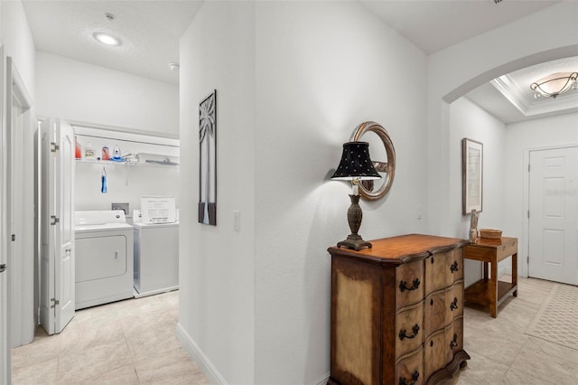 hallway with light tile patterned floors, washing machine and dryer, arched walkways, crown molding, and baseboards