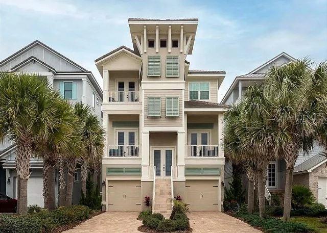 raised beach house with french doors, a garage, decorative driveway, and a balcony